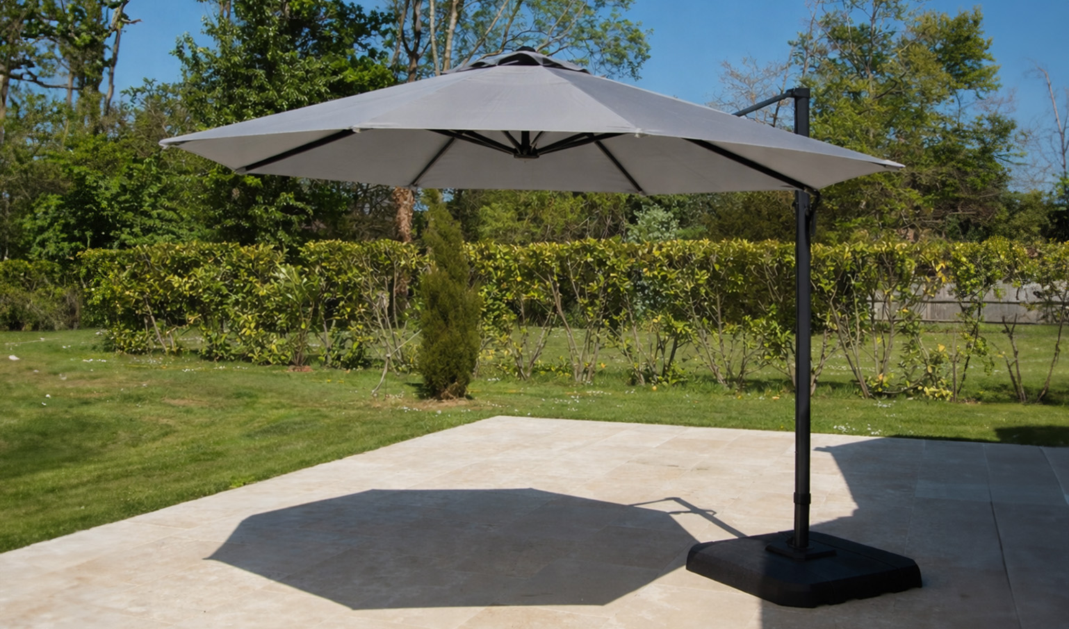 Large cantilever sunshade on a modern patio beside a green garden.